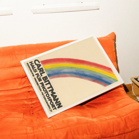 Minimalistisches Vintage-Plakat mit einem großen bunten Regenbogen und schwarzer Typografie unten.