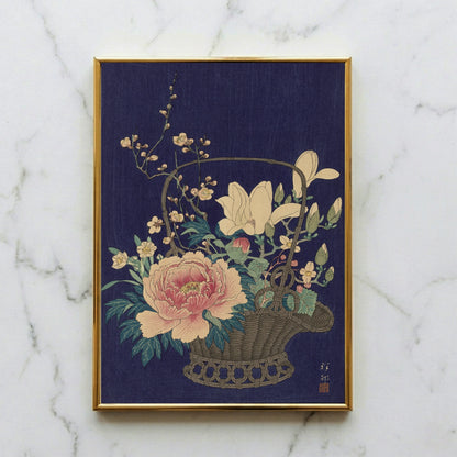 Japanischer Farbholzschnitt von Ohara Koson mit einem geflochtenen Bambuskorb voller Blumen vor dunkelblauem Hintergrund.